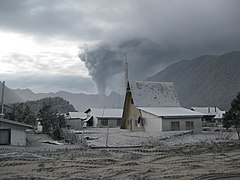 火山灰が降り積もった建物と噴煙を上げるチャイテン山、2008年6月