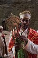 A priest stands with the Lalibela Cross after blessing Sunday worshippers.