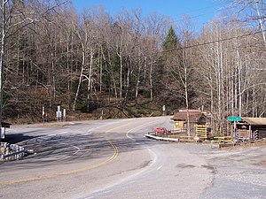 A small country store on the right side of the curving road is surrounded by hills and rugged landscape at Chimney Corner.