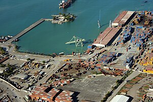 An aerial view of the seaport. Note the cargo containers floating out at sea and lopsided cranes.