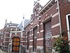 Administratiekantoor/ingang van de Doopsgezinde Kerk gebouwd pand, voorzien van een poortvormige ingang opgetrokken in baksteen, afgewisseld met natuurstenen blokken en banden en uitgevoerd in een mengvorm van neorenaissance en Jugendstil