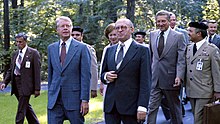 Carter, Begin, and Brzezinski walking together outside.