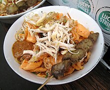 Bubur ayam dengan sate hati ayam, jajanan jalanan populer di Indonesia.