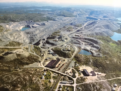 Luftbild einer von Kiesgruben, Straßen und Seen geprägten Landschaft, im Vordergrund ein Industriegebäude