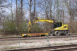 Zweiwegebagger 922rail von Liebherr beim Transport von Schienen im Bahnhof München-Riem. Er fährt im Auftrag der Bahnbaugruppe München.