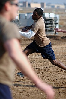 Offensive touch football player tries to get out of reach of defending player. US Navy 080112-N-7367K-006 Builder 3rd Class Bryan Williams, assigned to Naval Mobile Construction Battalion (NMCB) 1, Task Force Sierra, scrambles out of a defender's reach in a two-hand-touch football game during the detachme.jpg