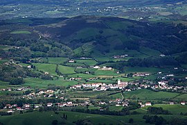 Vue aérienne d’un village dominé par des collines.