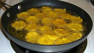 Patacones are twice-fried plantain patties, often served as a side, appetizer, or snack. Here they are being fried for the second time