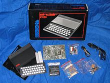 The component parts of the ZX81, including the case, keyboard and circuitry, resting on a blue sheet in front of the cardboard box in which it was shipped.