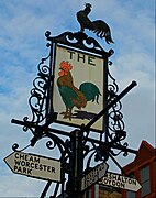 A finger post in Sutton town centre, London, incorporating the sign of the former Cock inn