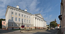 gray stucco building three story building with gray slate hip roof, central portico and pediment