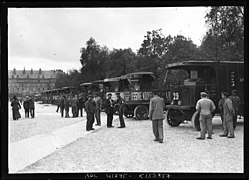 Photo noir et blanc avec file de camions le long d'une rangée d'arbres.