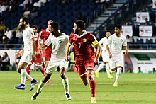 Hassan Maatouk and a Saudi player running while looking in the same direction