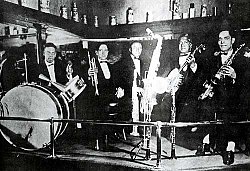 Barbarin, left, plays drums with a band on Rampart Street in New Orleans, 1919. Also pictured are (left to right): Arnold Metoyer, trumpet; Luis Russel, piano; Willie Santiago, banjo; Albert Nicholas, saxophones and clarinet.