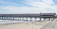 A long building built on a narrow pier extending out from the beach to the ocean