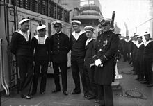 Photographie en noir et blanc de six marins, sur le pont d'un navire.