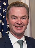 A photograph of Christopher Pyne looking into the camera in front of an American flag