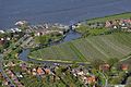 Luchtfoto van een deel van Grünendeich. Links, aan de Elbe, de veerboot aan de steiger, en rechts de stormvloedkering in het riviertje de Lühe.