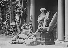 Devant le siège du NWP, deux jeunes femmes élégantes posent derrière des malles et des valises entassées sur le trottoir.