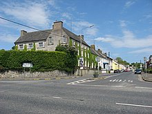 The is an image of Collon House located just off Drogheda street at the crossroads in Collon, County Louth on a sunny day. Green hedges surround the house making it more private from the streets.