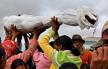 Famille de Madagascar portant le corps d'un de leurs ancêtres après l'avoir exhumé et en avoir changé les linceuls, lors du famadihana.