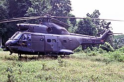A large helicopter in a jungle clearing.