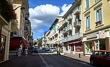 Vue en couleurs d'une rue commerçante et centrale d'une ville.