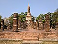 Grand wihan aux escaliers et sol en briques, aux colonnes en latérite avec en arrière-plan le chedi principal du temple sur un axe est-ouest.