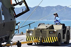 Remorqueur EINSA sur le pont du porte-aéronef HMAS Canberra tractant un hélicoptère.