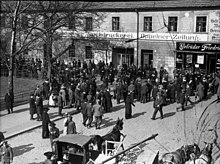 A large number of people crowd outside a building.