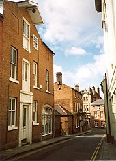 An early warehouse building, with loading doorways on three floors and a simple lucarne above formed merely by the roof projecting beyond the wall and supporting a single pulley