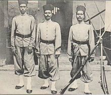 Photographie en noir et blanc d’hommes en tenue sévère.