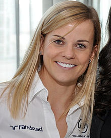 Photographie d'une femme blonde, de face, souriante, en gros plan, avec une chemise blanche.