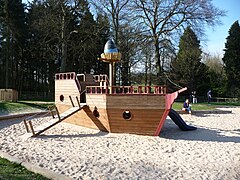 Portique de jeu à thème au sein d'un bac à sable, le bateau est creux et constitue une maisonnette de jeu