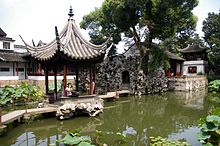 Constructions légères et plantes diverses autour d'une petite rivière.