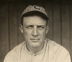 A man in a striped white baseball jersey wearing a striped gray baseball cap with a "C" at the centre.