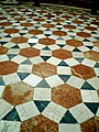 Sol en carrelage d'une église à Séville, en Espagne. Des pavés triangulaires et carrés entourent un pavé hexagonal marron