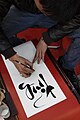 A calligrapher writing Tính, which means 'to ponder' or 'figure out'.