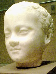 Three-quarter view of a sculpture of a young child's head, the child appears smiling his face has relaxed expressions as he gazes over the viewer's shoulders