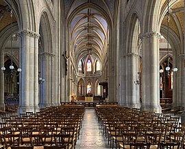 Photographie de la nef d'un édifice religieux occupée par des rangées de chaises tournées vers l'autel.