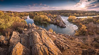 Vista panorâmica de uma área do Parque Nacional Gard de Buzk, na região de Mykolaiv, no rio Bug Meridional, Ucrânia. A área total do parque é de 6 138,13 hectares e está localizado na encosta sudoeste da maior região geoestrutural da Ucrânia — o Escudo Cristalino ucraniano. Um planalto com declives suaves destaca-se no parque. O planalto é dividido pelos vales dos rios Bug Meridional, Mygiy Tashlyk, Korabelna, Mertvovod, Arbuzinka e Bakshala em áreas separadas, que por sua vez são divididas por uma rede de córregos e ravinas, a maior das quais flui diretamente para o vale do rio Bug Meridional. (definição 5 000 × 2 781)