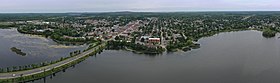 Aerial image looking down at angle showing lake in foreground and city beyond it.