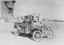 Photograph of a British armoured car with a driver and passenger outside Aleppo, with a white flag of truce set on it