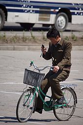 Un ciudadano de Corea del Norte monta una bicicleta en Hamhung mientras usa un teléfono celular.