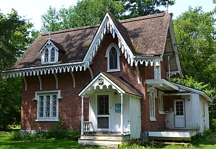 Cachée derrière une rangée d'arbres, cette maison se dévoile après quelques pas dans une clairière. Maison du jardinier du manoir Louis-Joseph-Papineau à Montebello dans la région de l'Outaouais au Québec.