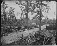 Black and white photo shows a road and some field fortifications.