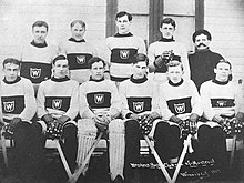 Several rows of men, some wearing hockey uniforms, the others in overcoats and top hats.