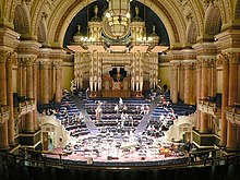 A large decorated hall with a pipe organ and stage