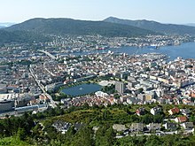 Blick von einer Anhöhe herab auf eine Großstadt, rechts im Bild ist das Meer zu sehen