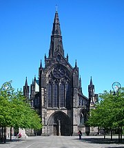 black weathered stone cathedral showing west front stained glass window